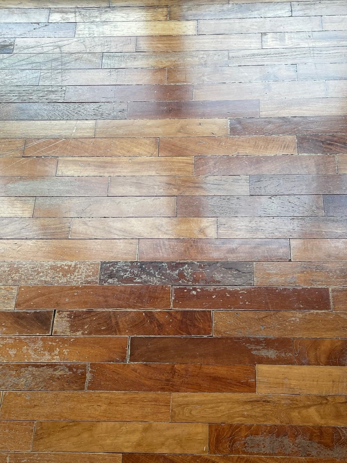 A patchy, unevenly worn parquet floor — a common case for repair rather than full replacement